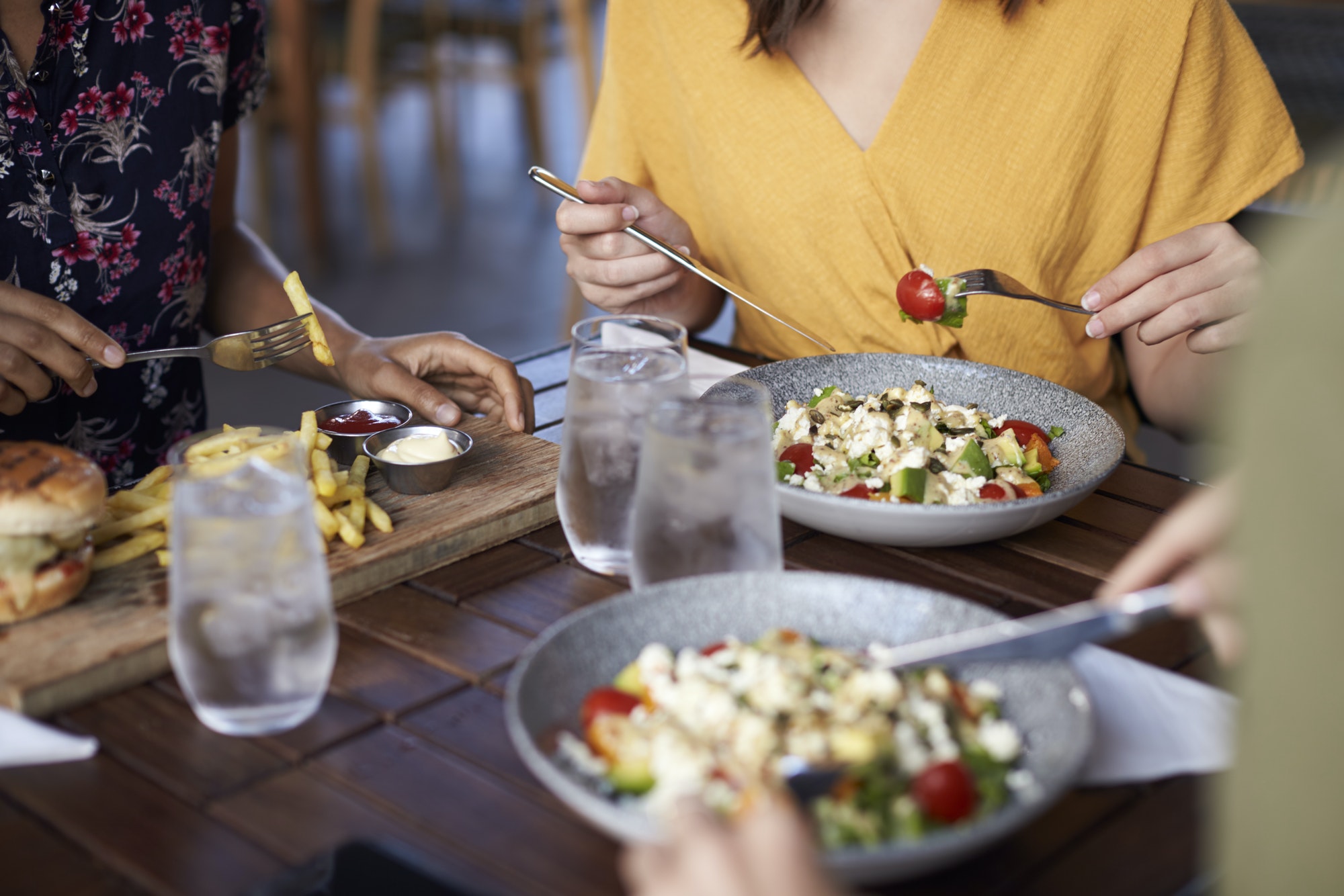 close-up-of-female-friends-eating-food-at-table-in-restaurant.jpg